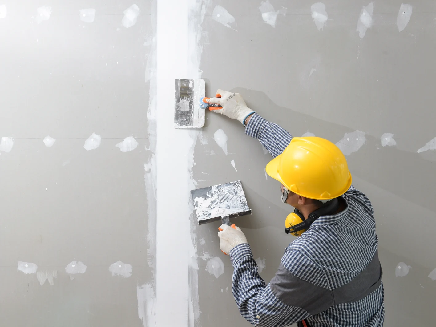 interior decoration construction furniture builtin.Plasterer in working uniform plastering the wall indoors.