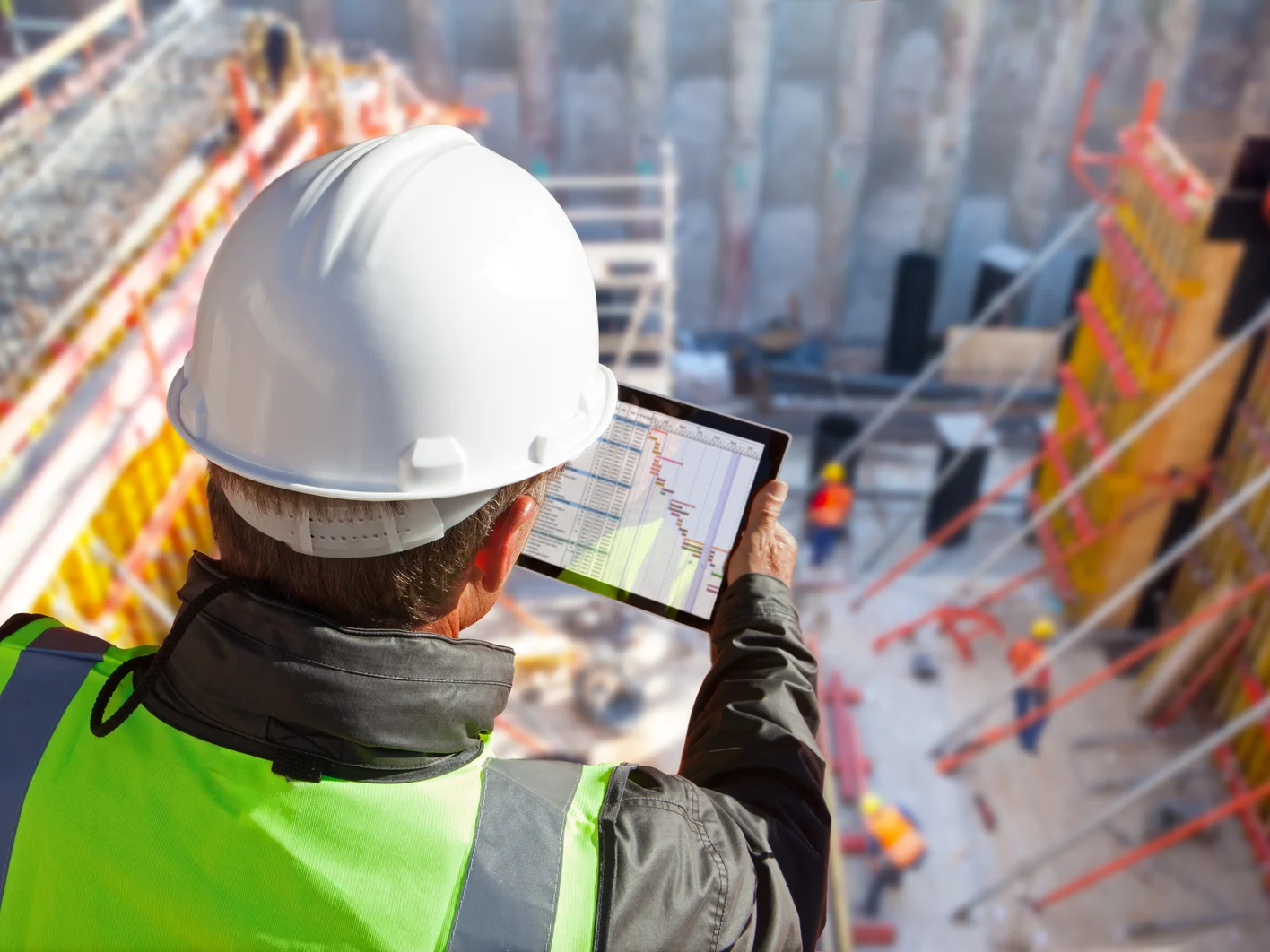civil engineer or architect on construction site checking schedule with tablet computer