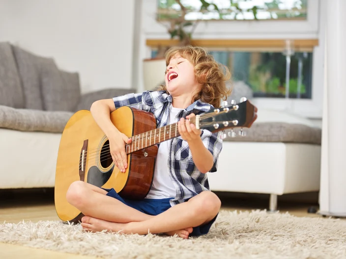 Junge beim Singen und Musizieren auf der Gitarre