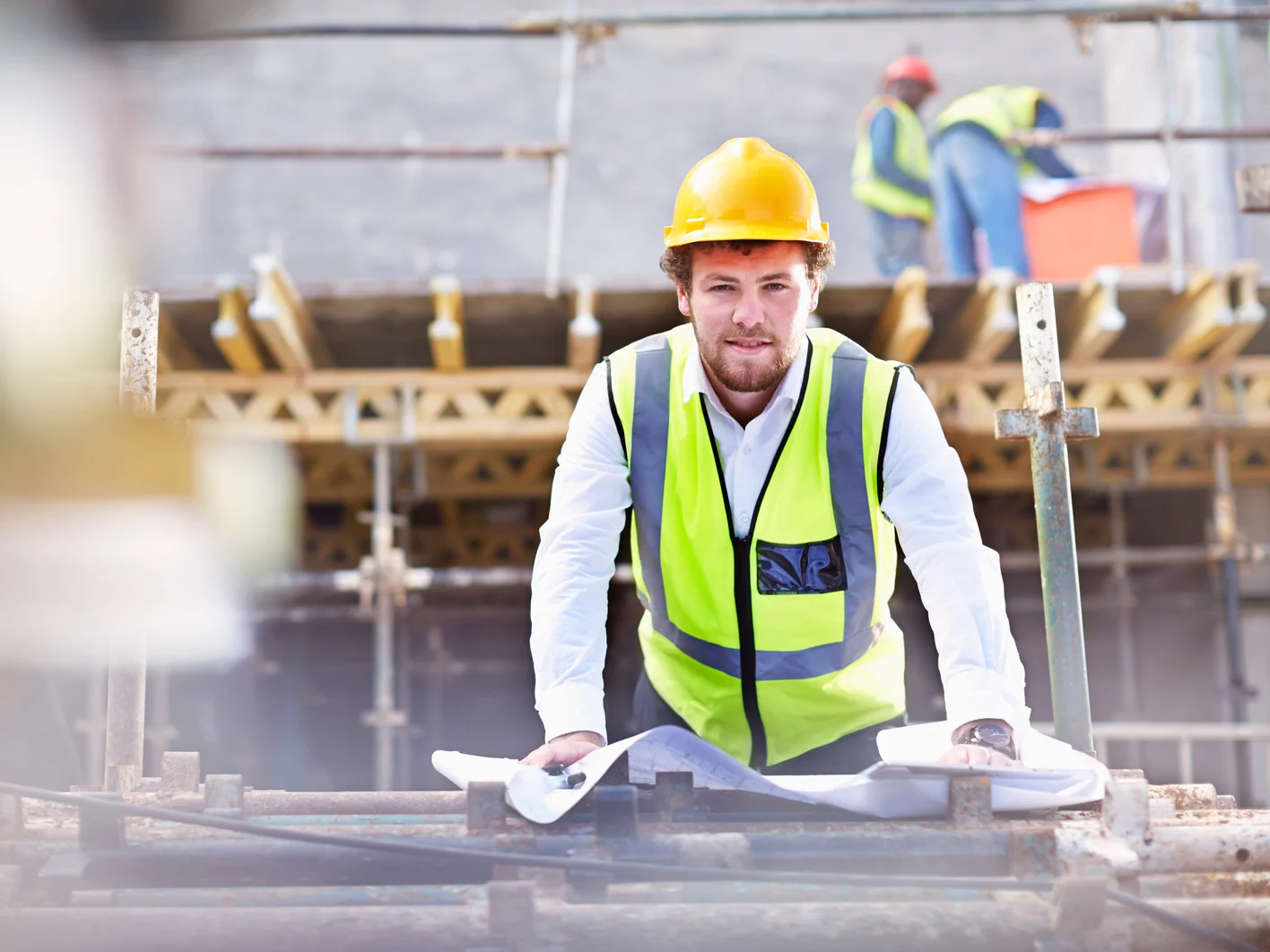 Portrait confident engineer with blueprints at construction site
