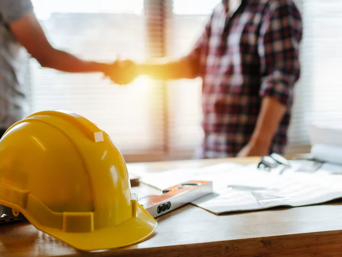 yellow safety helmet on workplace desk with construction worker 
