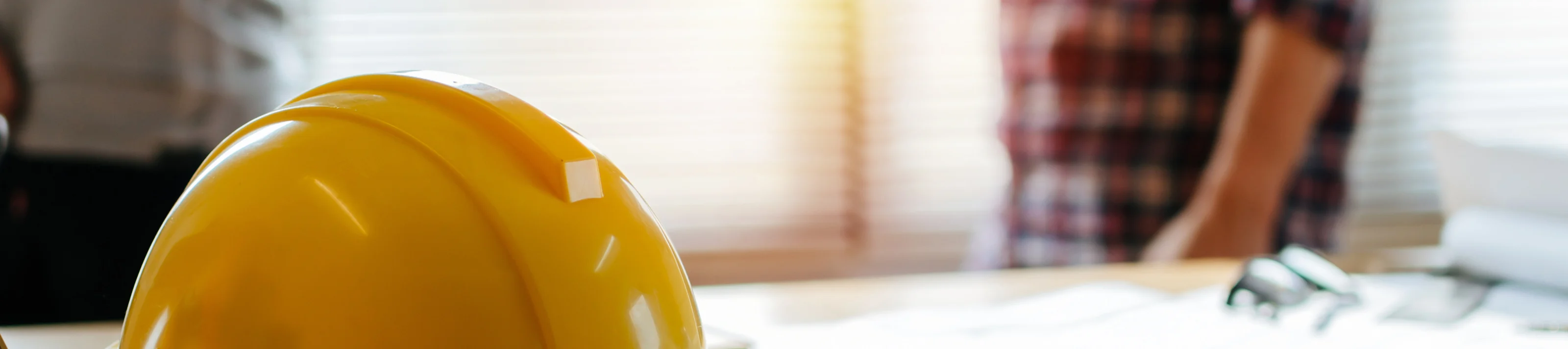 yellow safety helmet on workplace desk with construction worker 