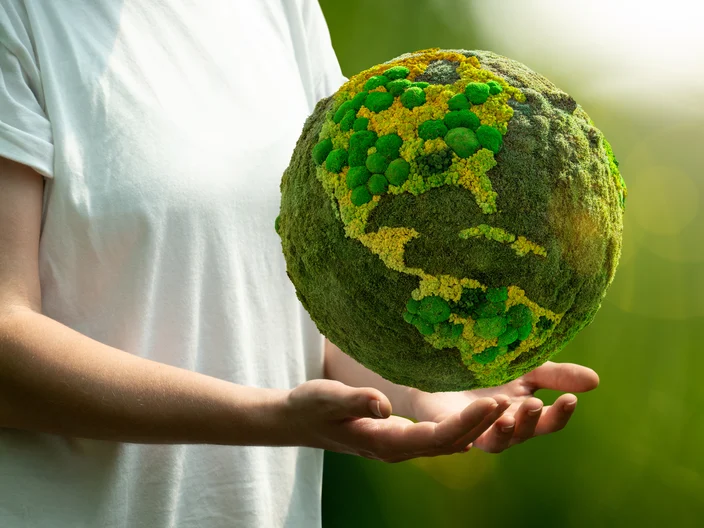 Woman holding a green planet Earth Symbol of sustainable development and renewable energy