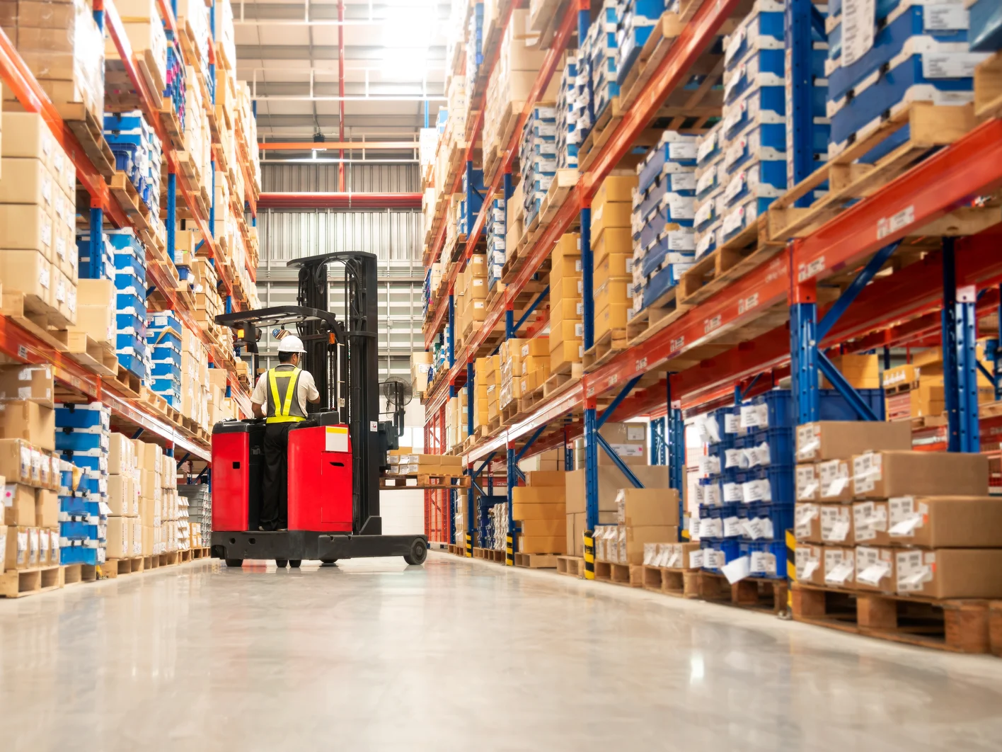 Worker in forklift truck loading packed goods in warehouse