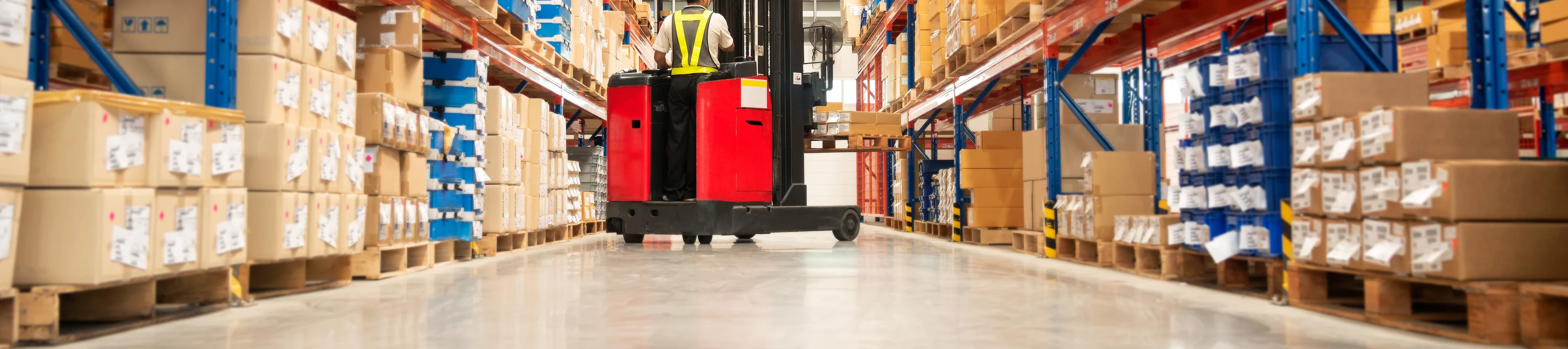 Worker in forklift truck loading packed goods in warehouse