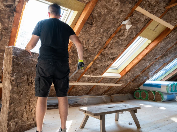 Craftsman cutting insulation material to insulate the attic.