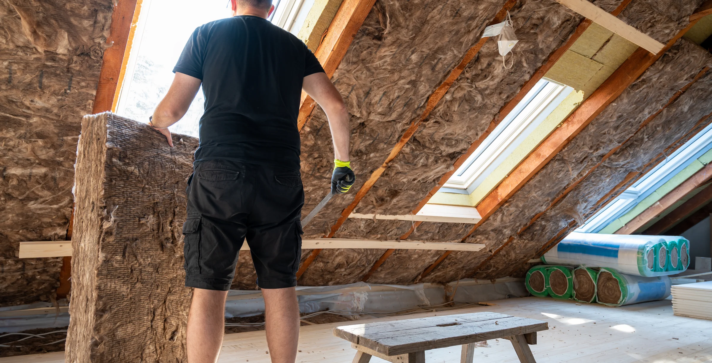 Craftsman cutting insulation material to insulate the attic.