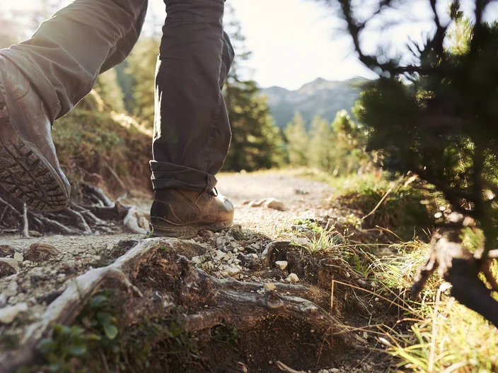 Wanderschuhe beim Laufen als Detail in Bewegung mit Fels und Steinen