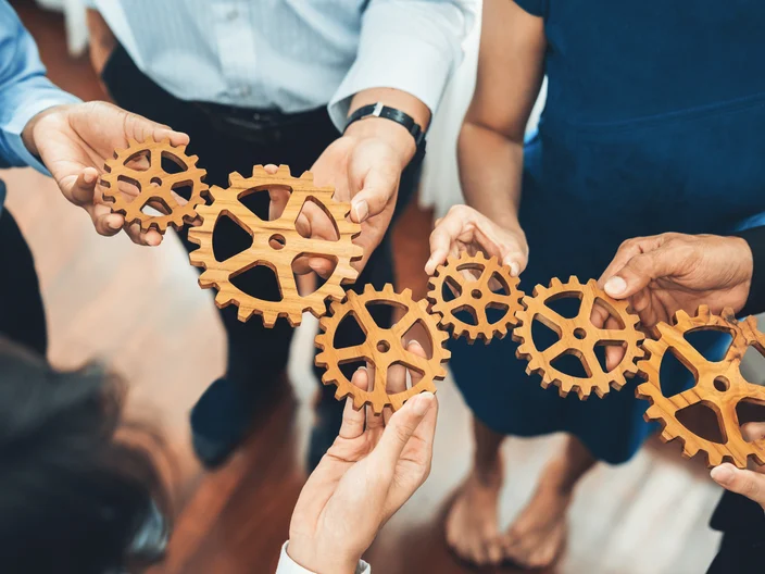 Office worker holding cog wheel as unity and teamwork in workplace. Concord