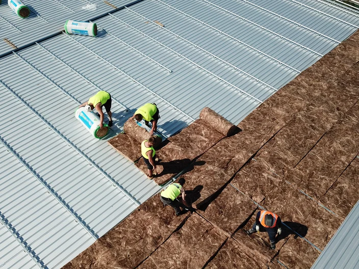 Men installing insulation under metal roof
