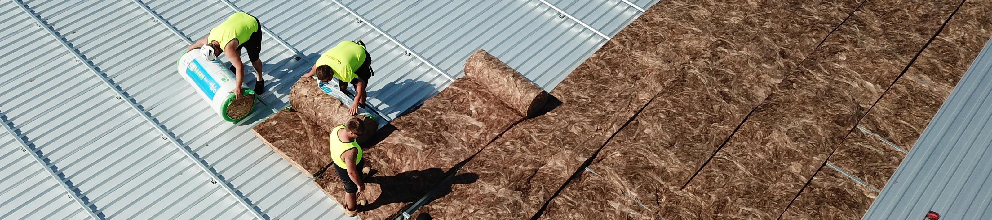 Men installing insulation under metal roof