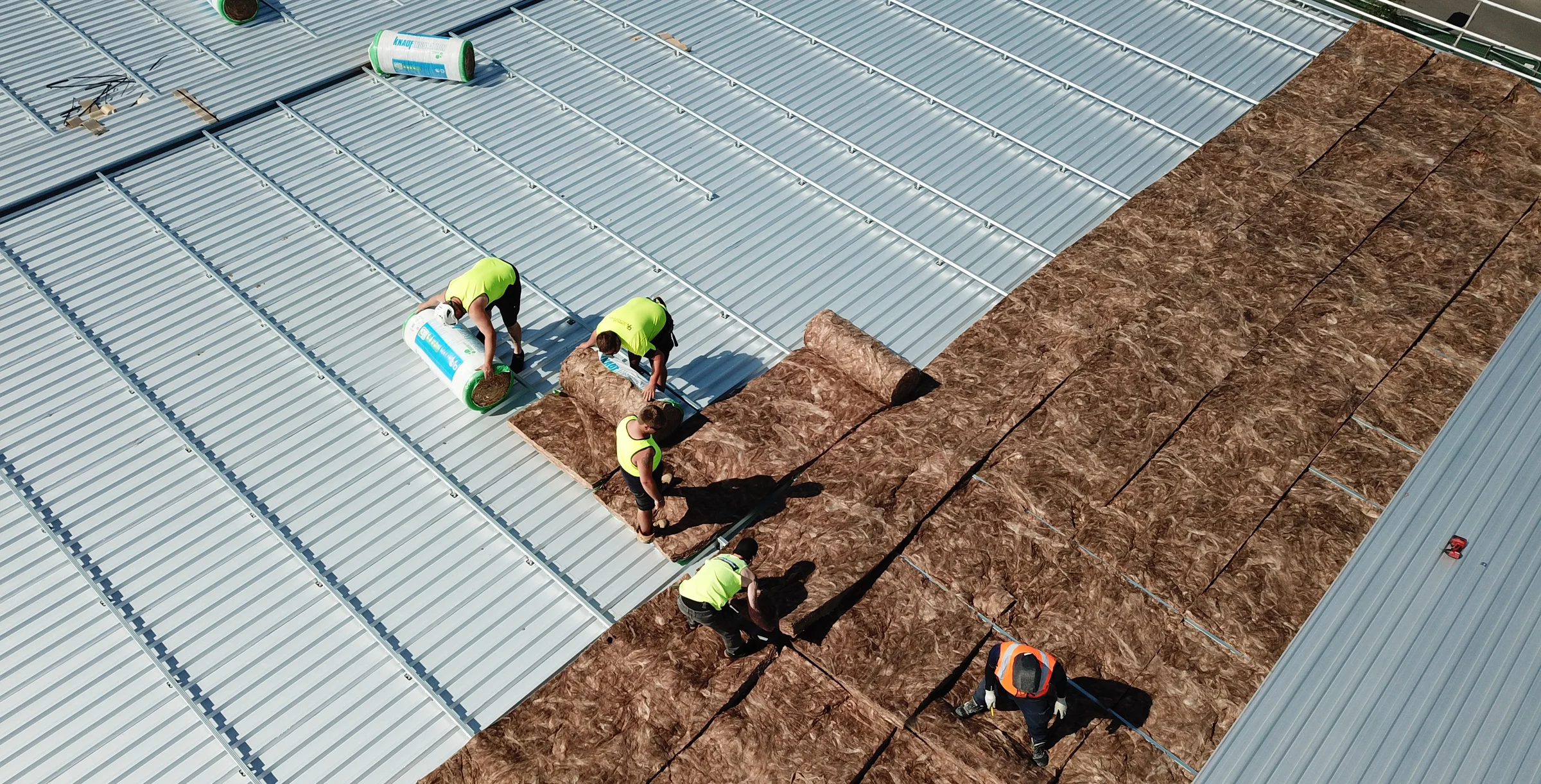 Men installing insulation under metal roof