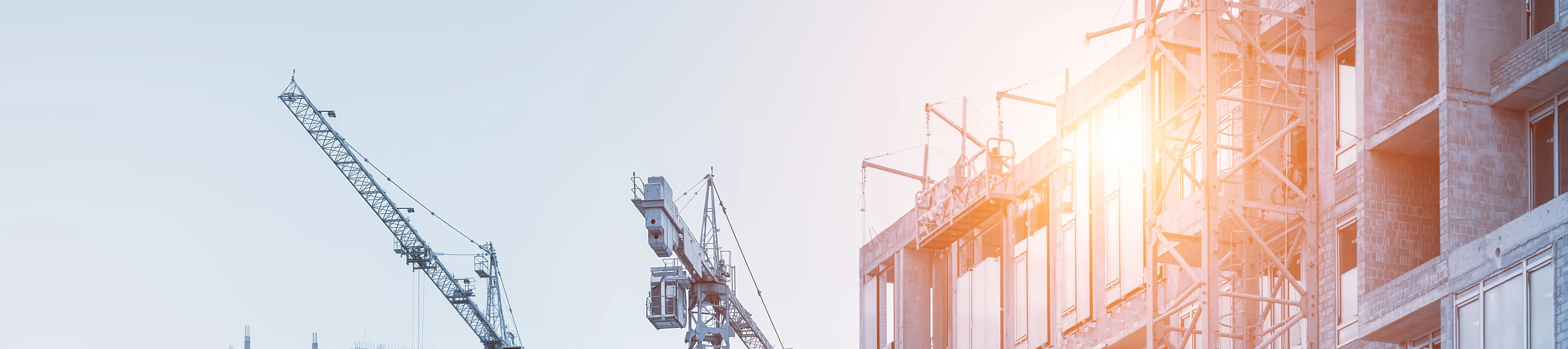 Modern apartment residential building glass facade wall construction site with many high tower cranes and heavy machinery against blue sky background. Industrial scenic urban city development project