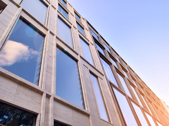 Abstract closeup of the glass-clad facade of a modern building covered in reflective plate glass. Architecture abstract background. Glass wall and facade detail.