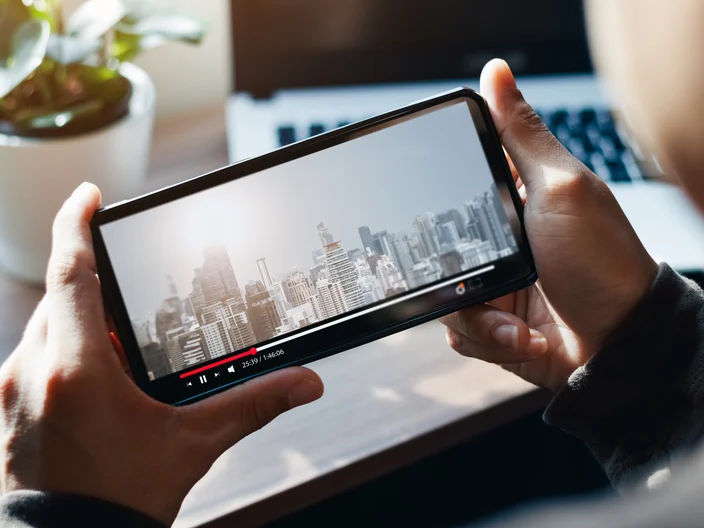 Online movie streaming with smartphone. Young man watching a movie on a mobile phone with an imaginary video player service.