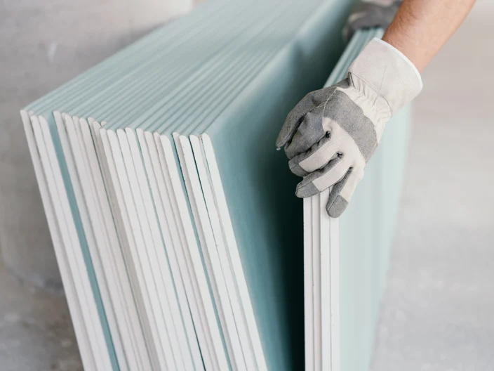Builder taking a sheet of chip board cladding