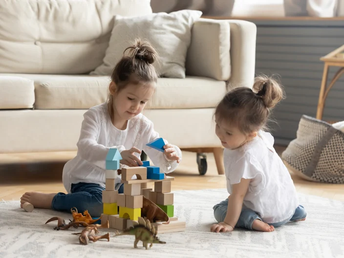 Two cute little girls playing on warm floor together