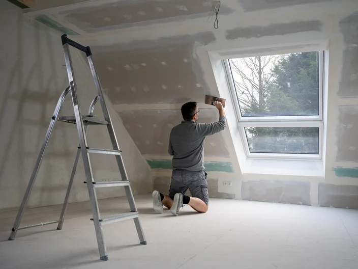Man plastering drywall in a private house.