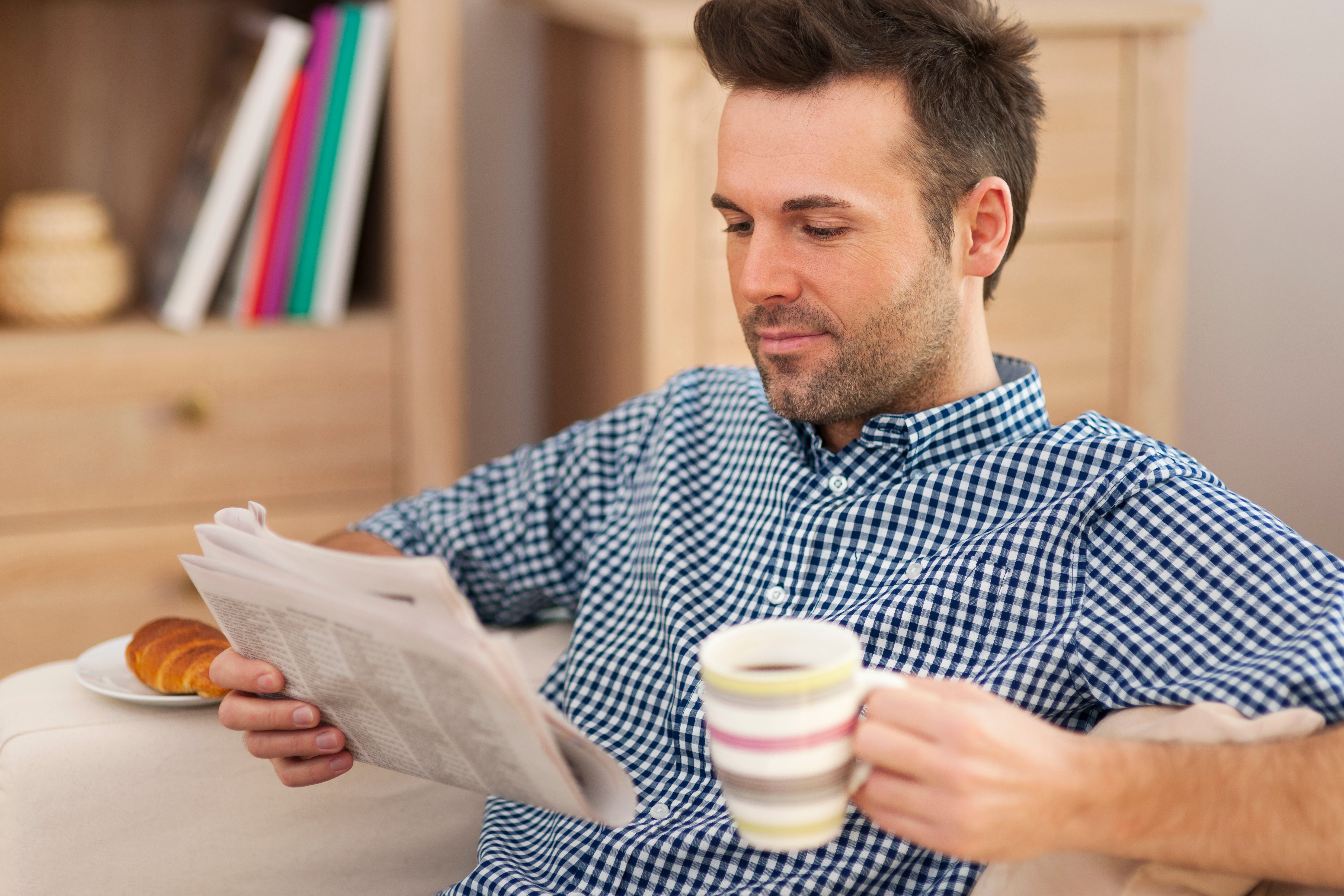 Smiling Man Reading Newspaper and drinking Coffee