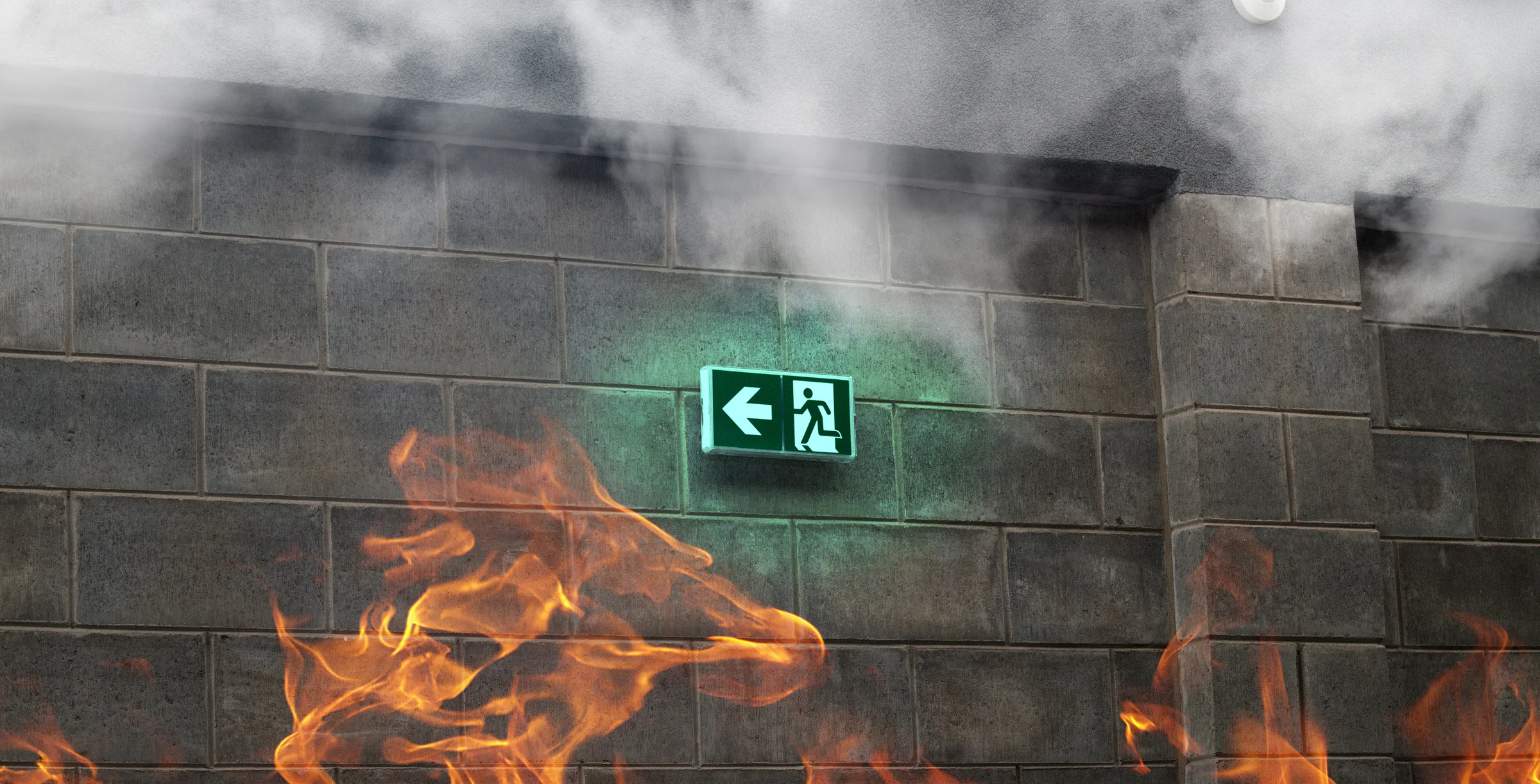 Emergency Fire Exit on the stone wall with fire and smoke