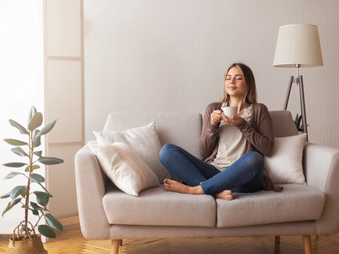 Young coffee lover sniffing hot drink at cozy home interior