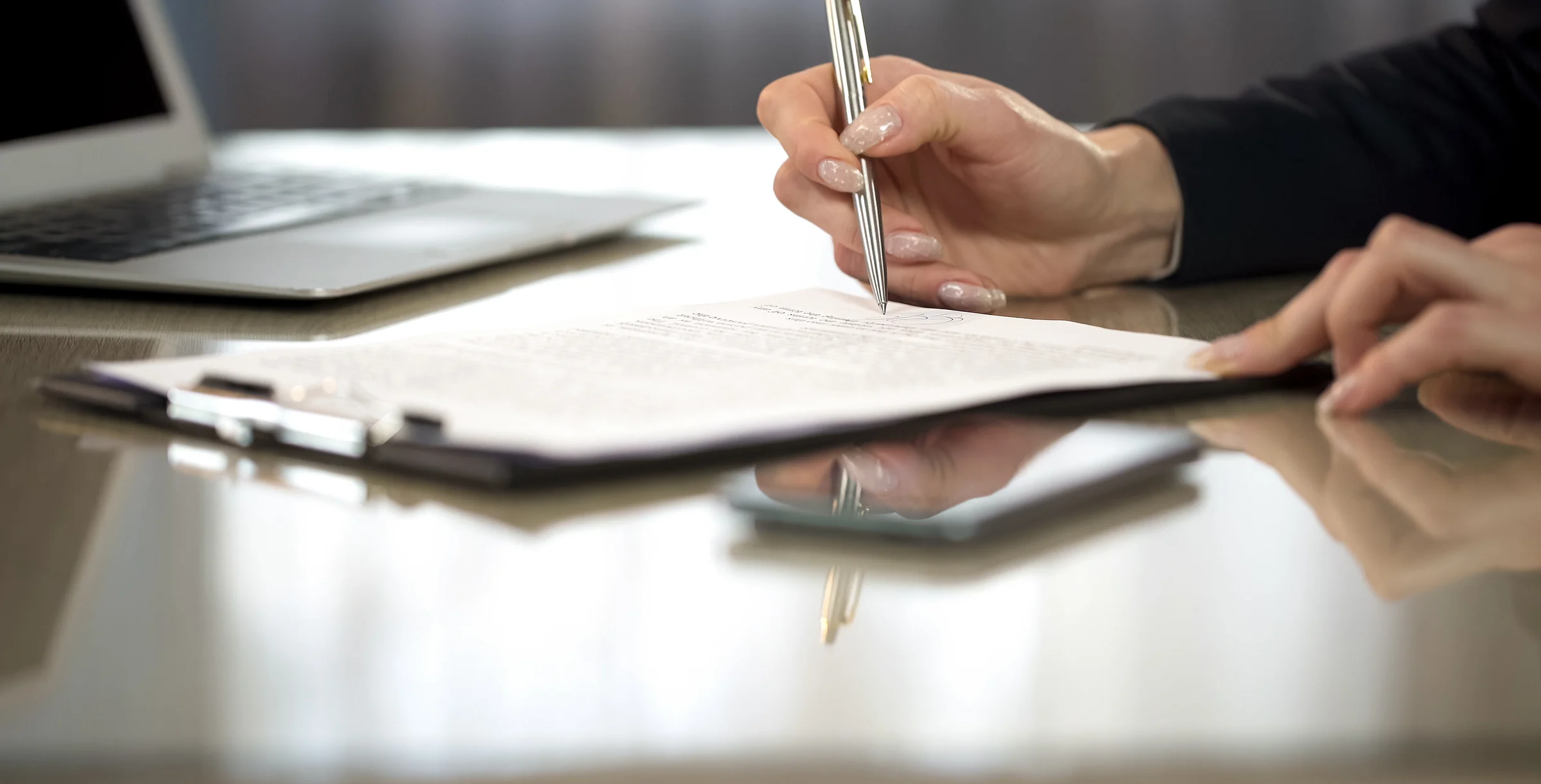 Woman in suit reading terms and conditions of agreement, signing contract