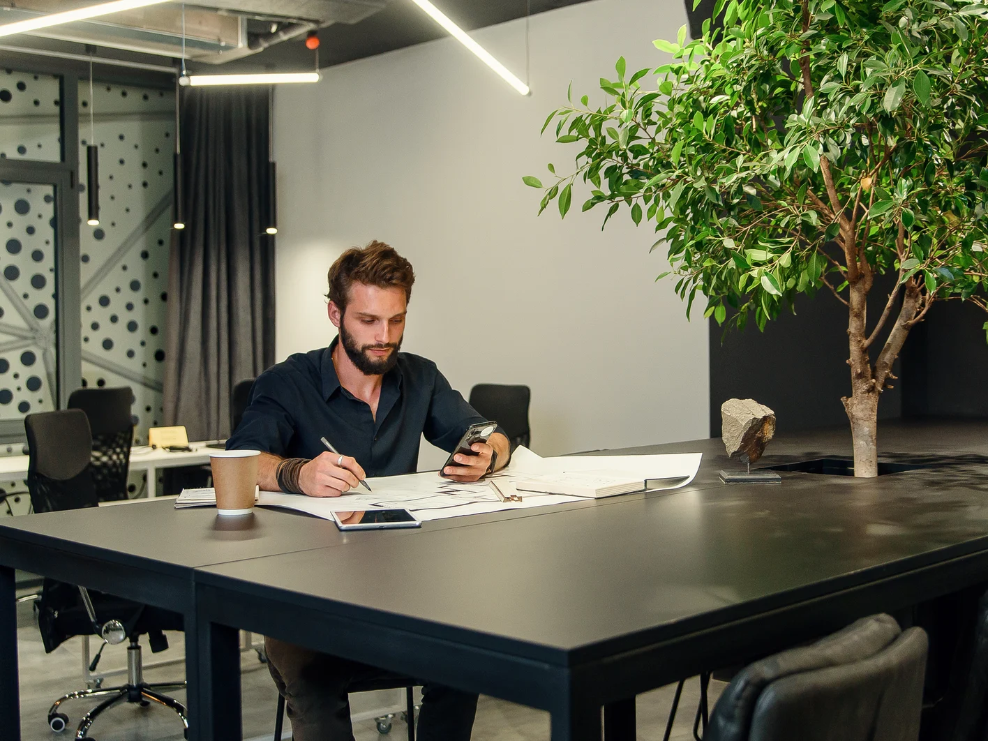 Young bearded architect working with scratches on his new project