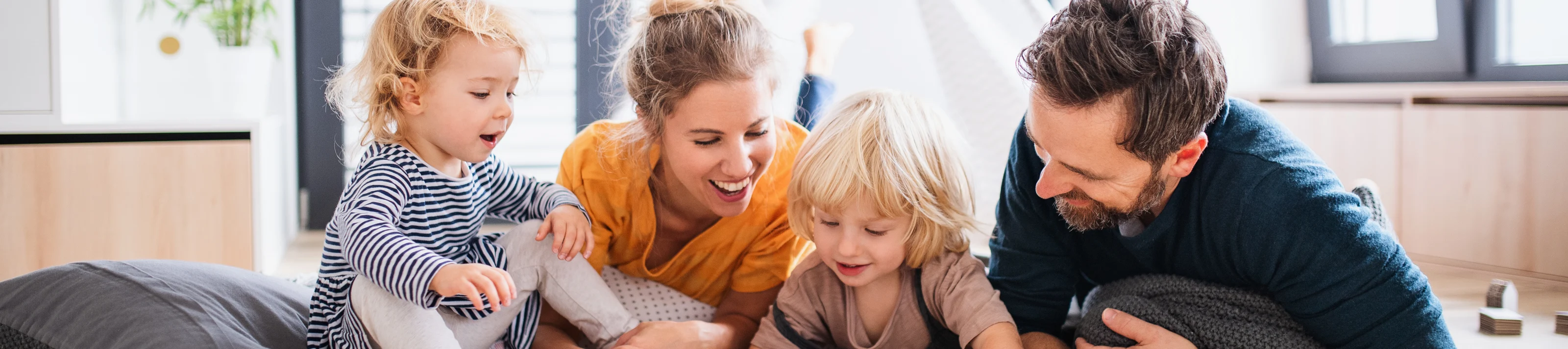 Young family with two small children indoors in bedroom reading 