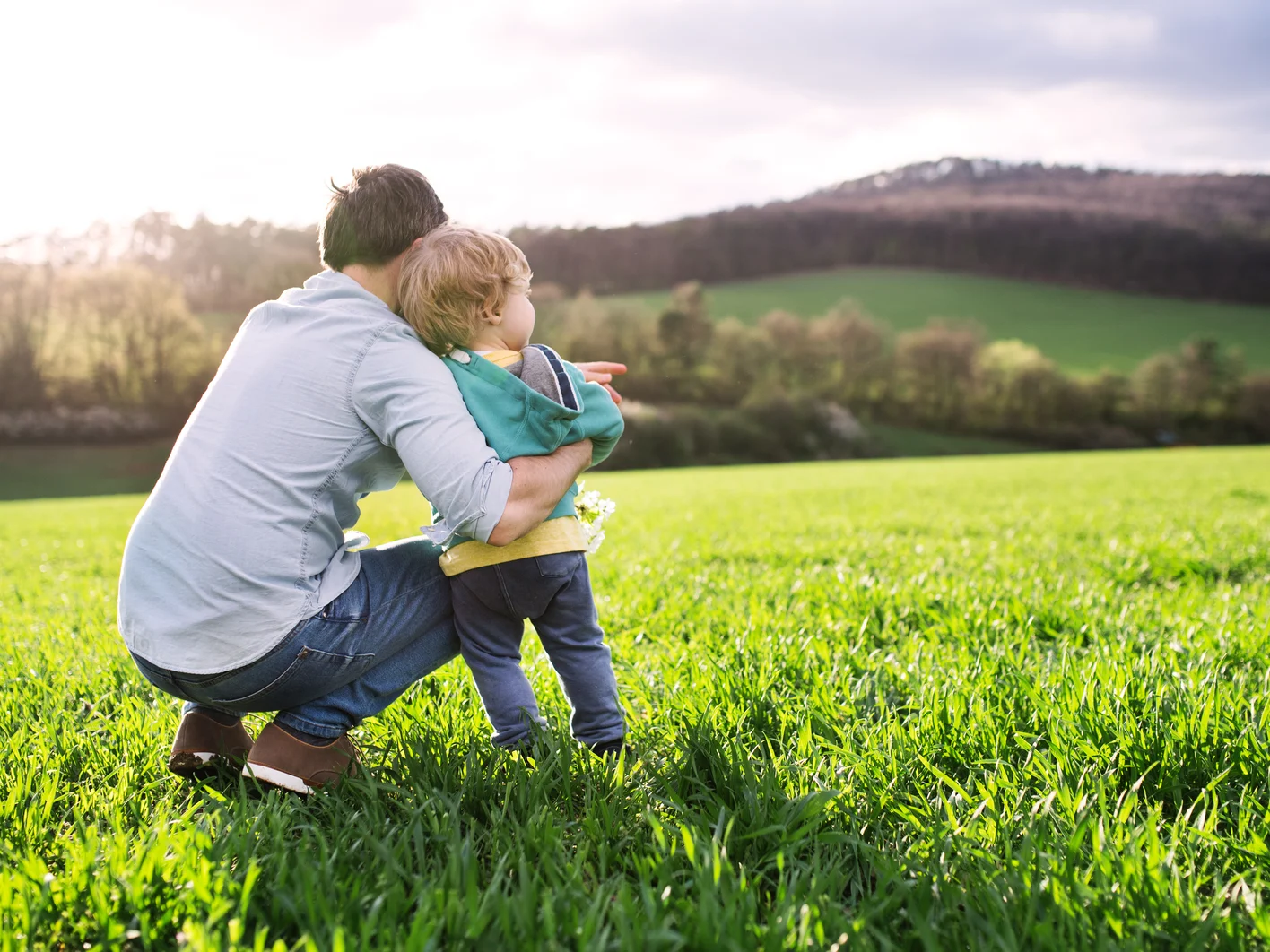 A father with his toddler son outside in spring nature. Copy space.
