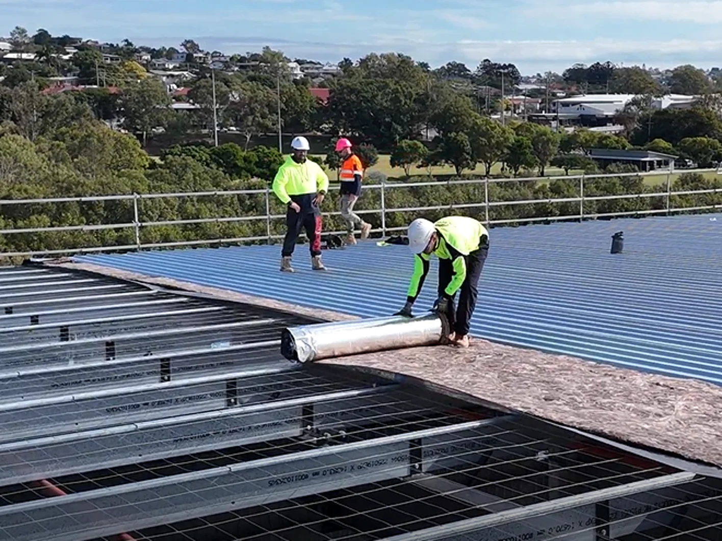 Installer rolling out metal roofing insulation