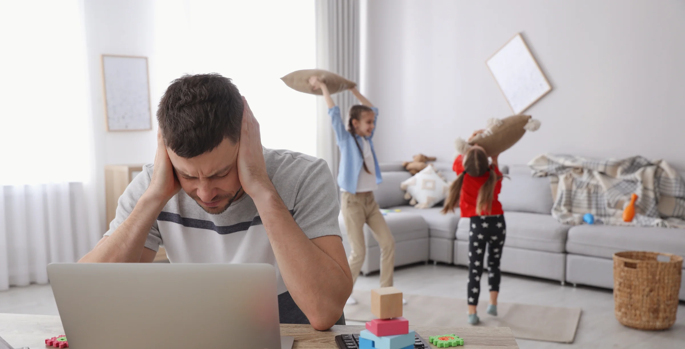 Children disturbing stressed man in living room. Working from home during quarantine
