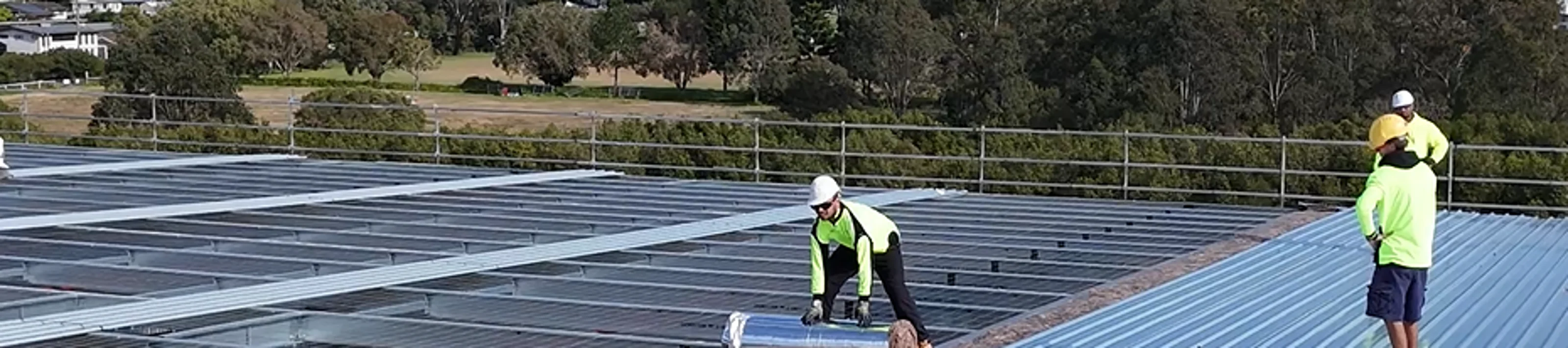 Installers installing insulation with metal roofing sheets
