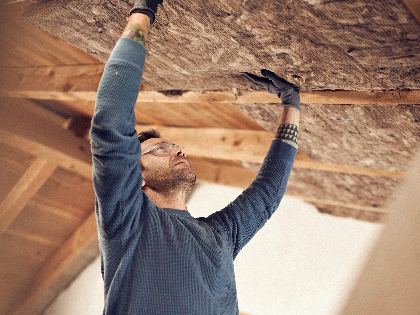 Man installing glass mineral wool in a ceiling