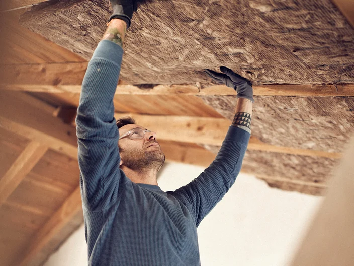Man installing glass mineral wool in a ceiling