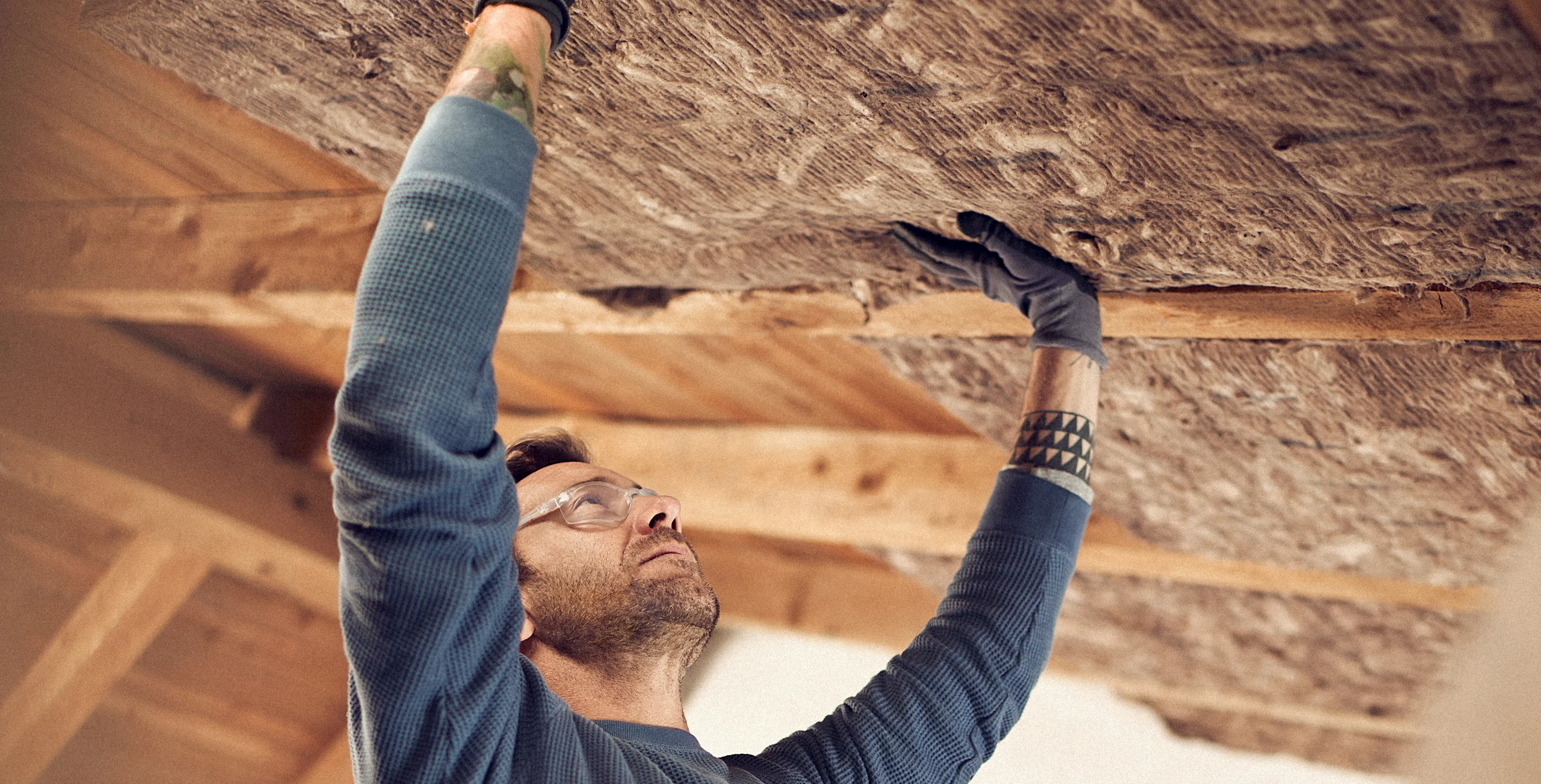 Man installing glass mineral wool in a ceiling