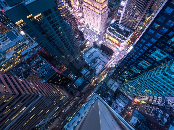 Bird's eye view of Manhattan, looking down at people and yellow taxi cabs going down 5th Avenue.