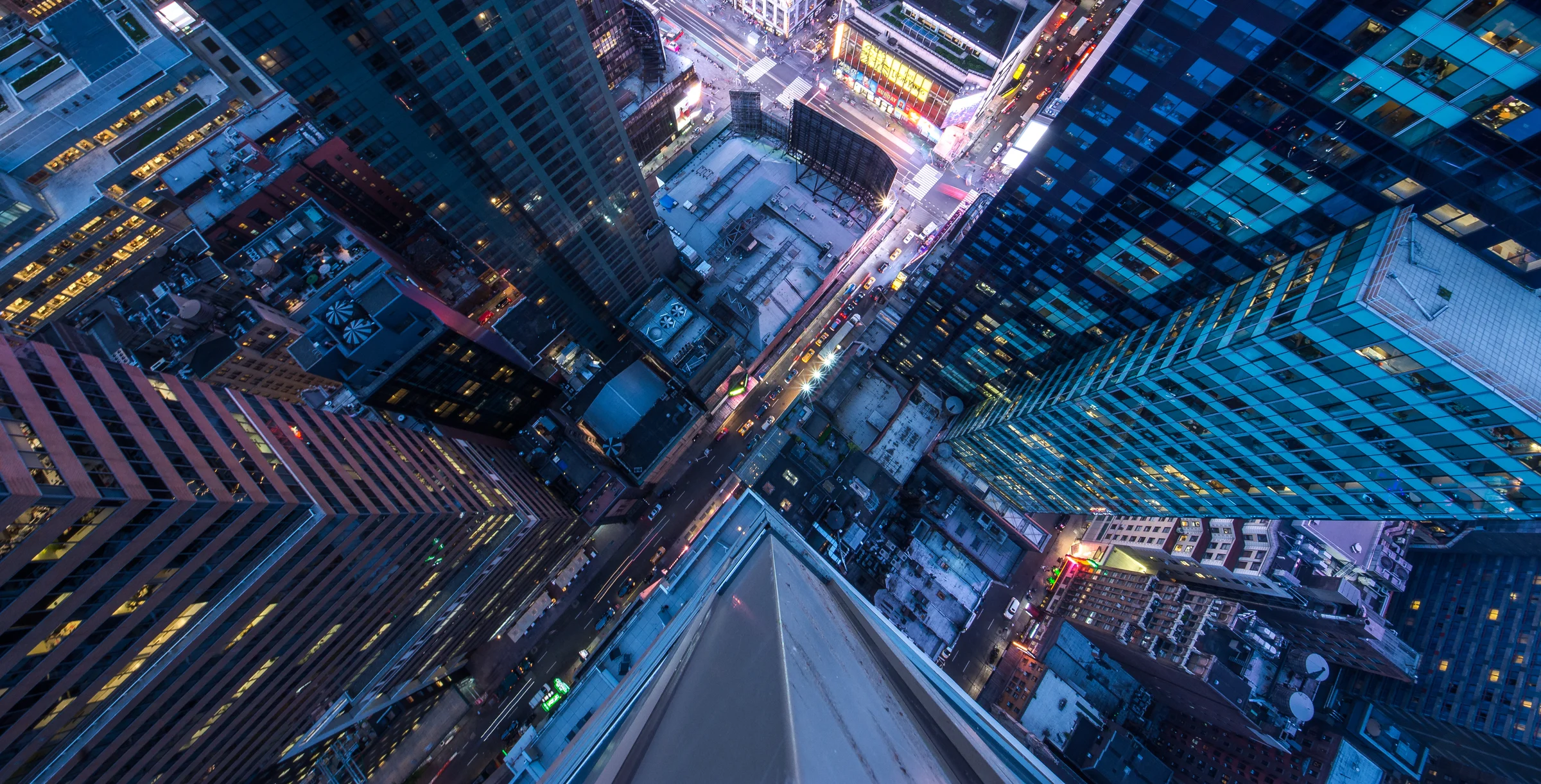 Bird's eye view of Manhattan, looking down at people and yellow taxi cabs going down 5th Avenue.
