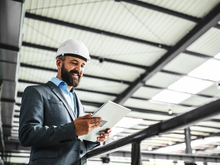 A portrait of an industrial man engineer with tablet in a factory.