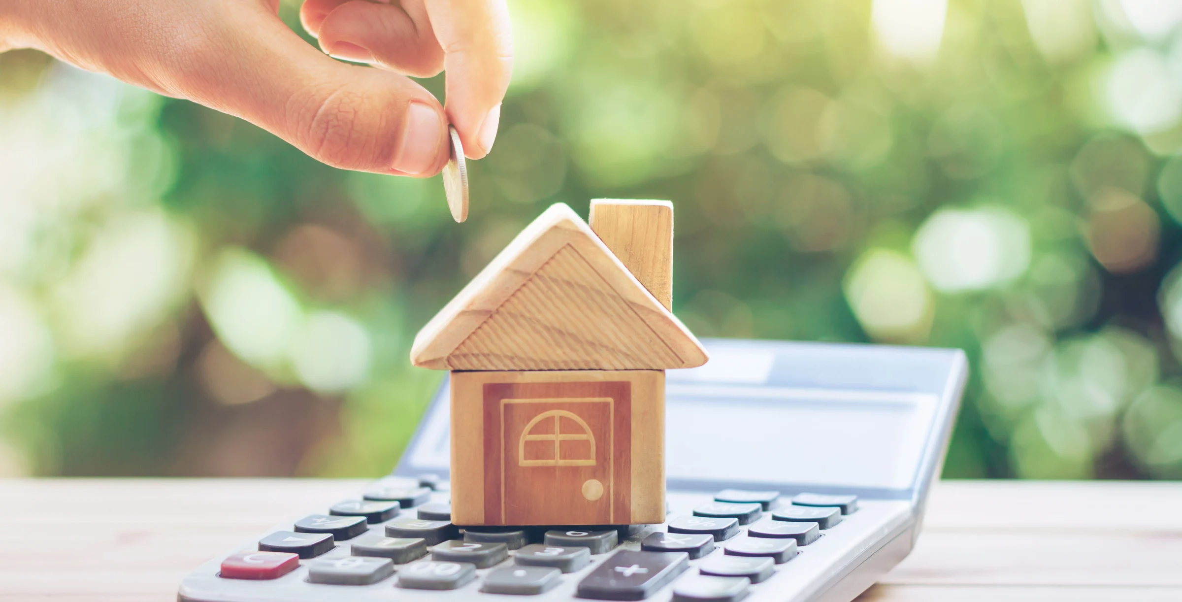 House is placed on the calculator. hand that is coin down the house. planning savings money of coins to buy a home concept for property, mortgage and real estate investment. savings to buy a house.