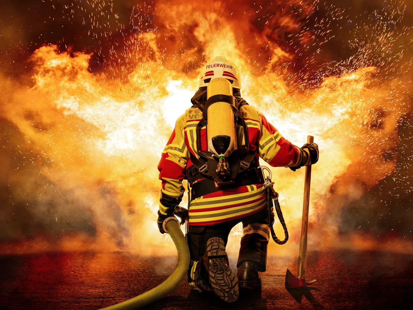 Feuerwehrmann kniet vor einem Feuer