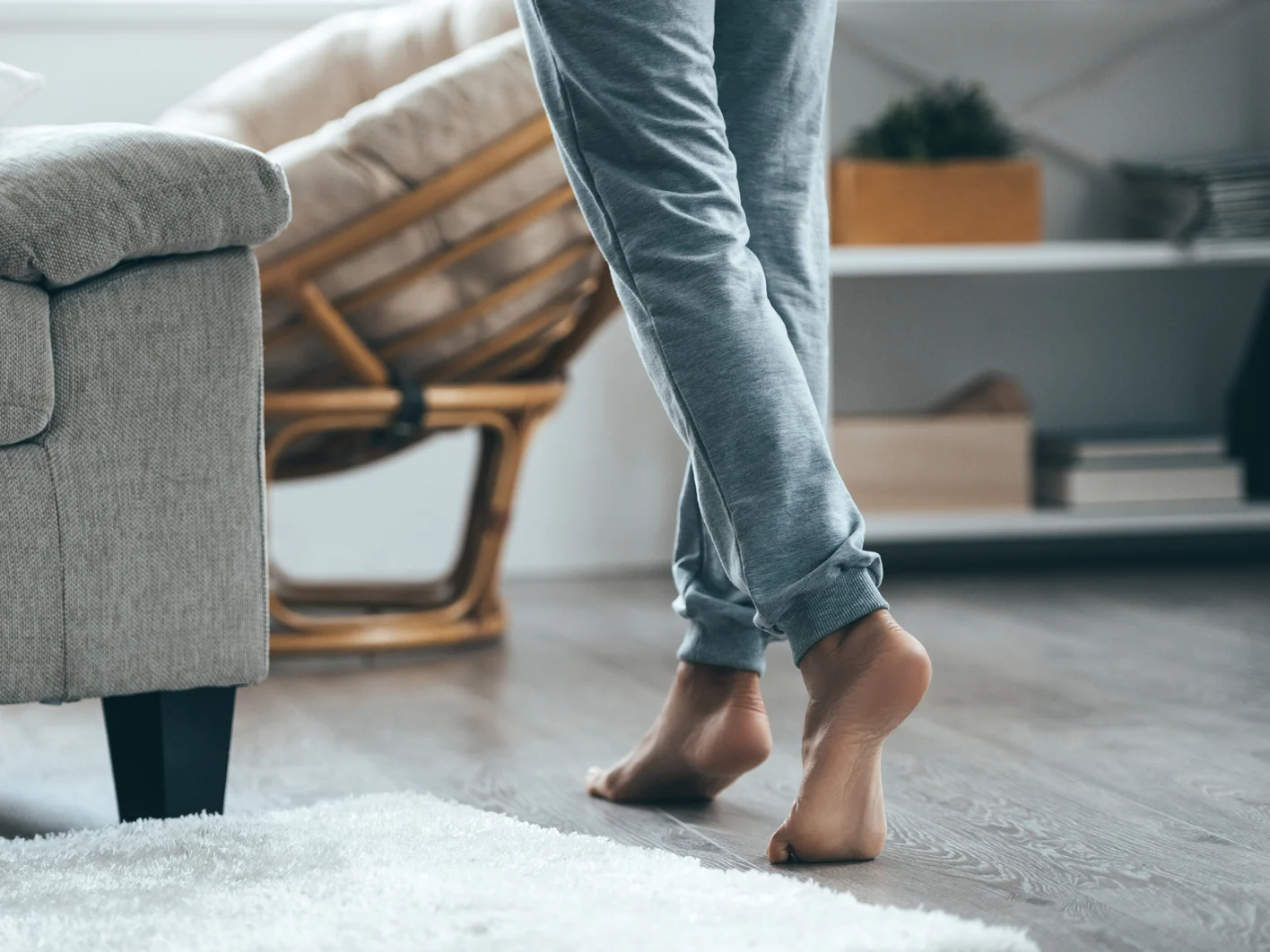 Warm floor concept. Close-up of female legs stepping by hardwood floor at home 