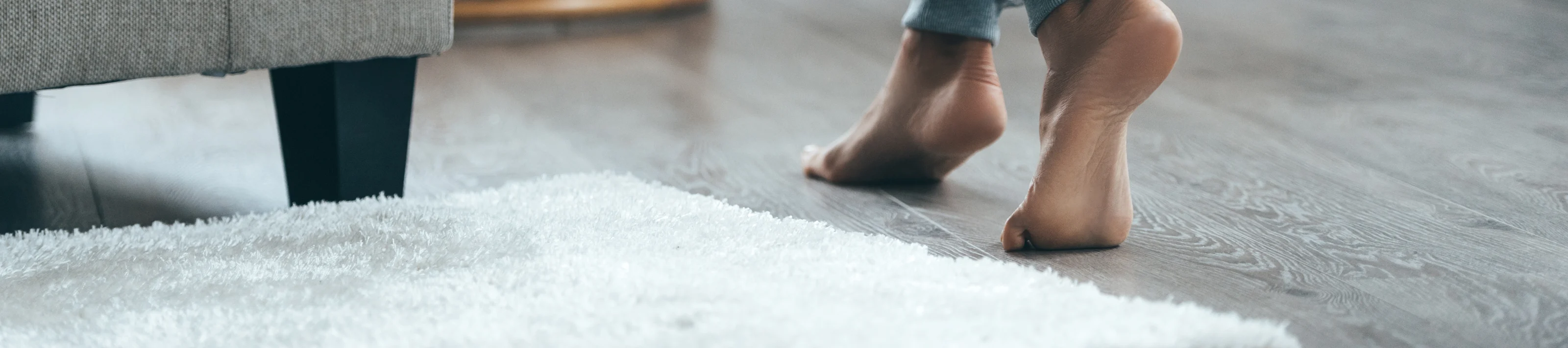 Warm floor concept. Close-up of female legs stepping by hardwood floor at home 