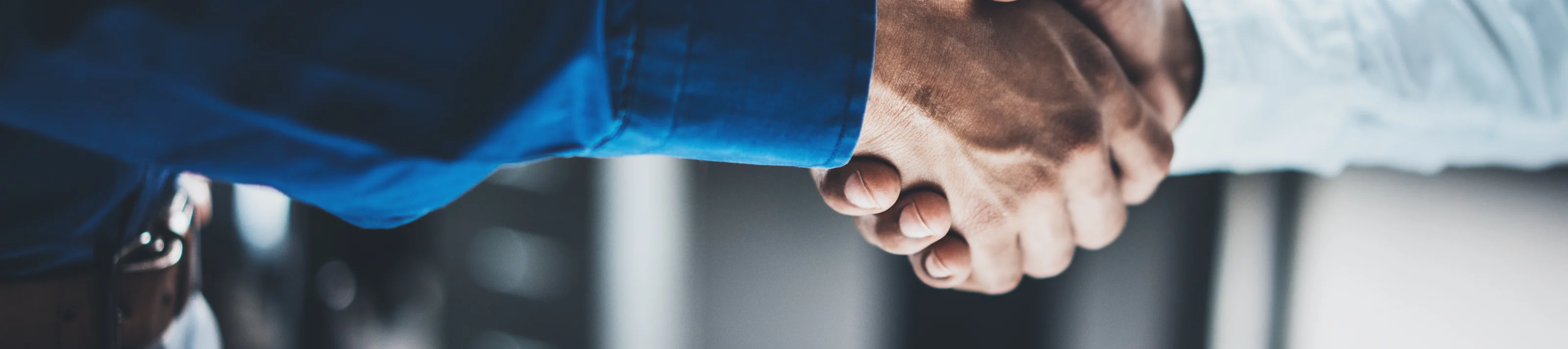 Business partnership handshake concept.Closeup photo of two businessmans handshaking process.Successful deal after great meeting.Horizontal, blurred background.