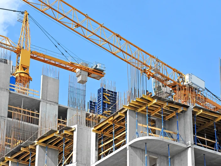 Crane and building construction site against blue sky