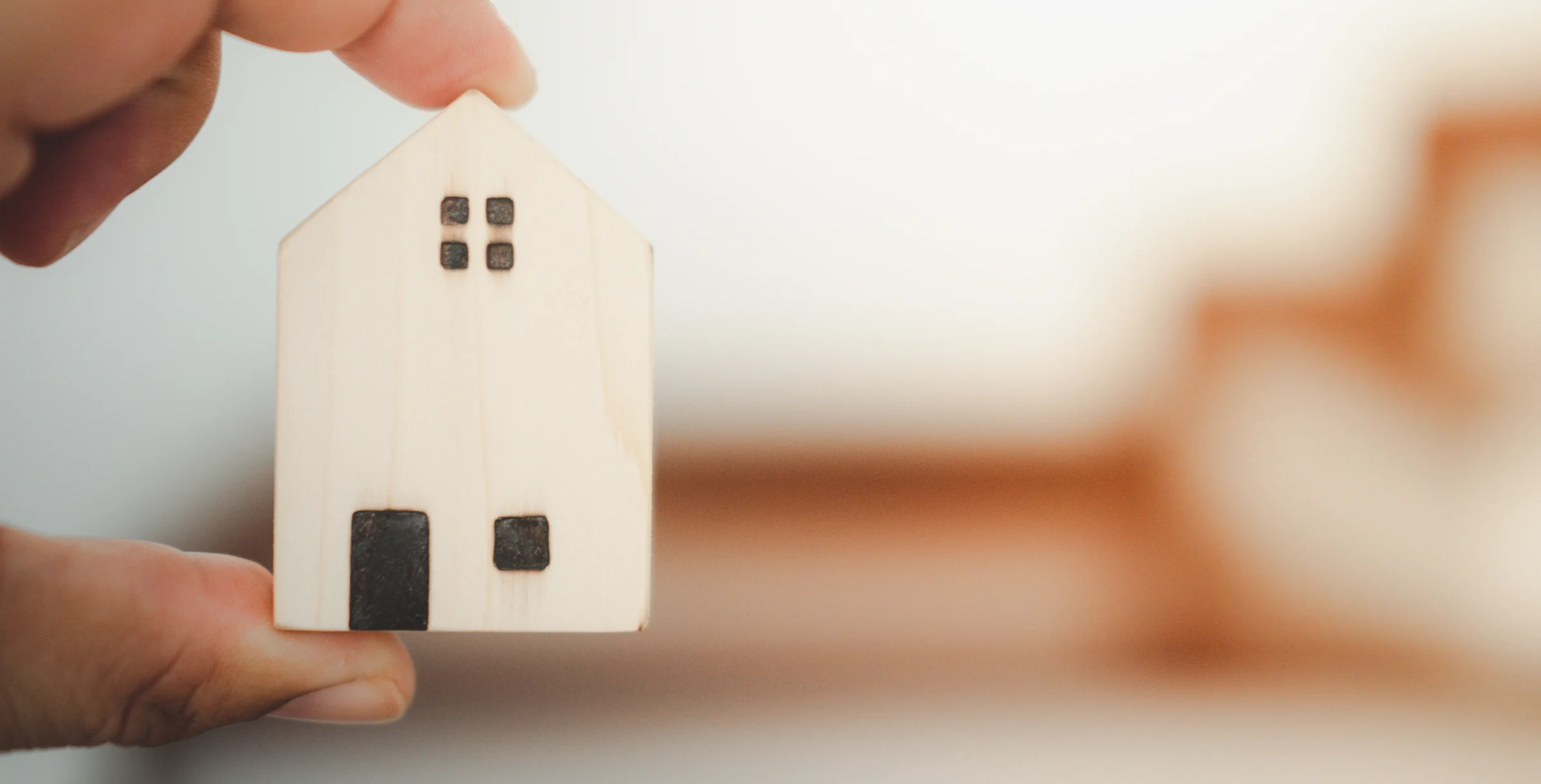 Male hands holding small toy house. 