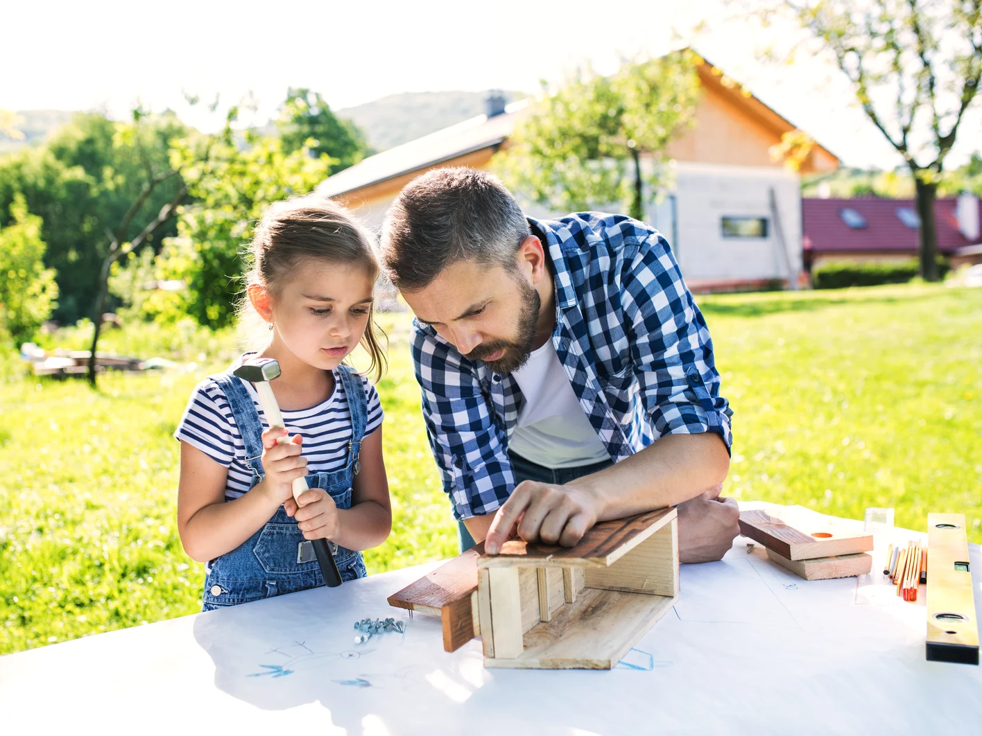 Father with a small daughter outside making wooden birdhouse