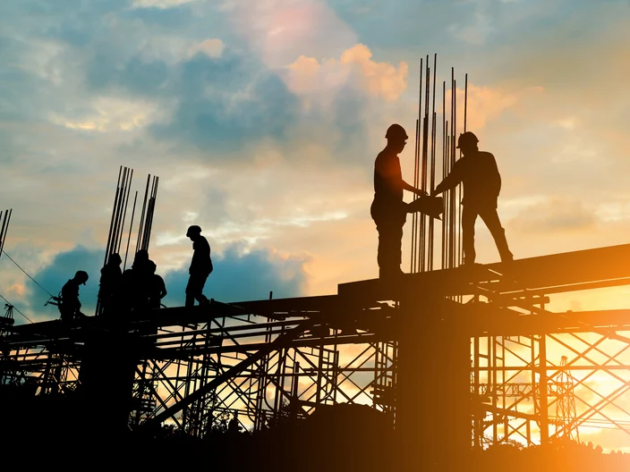 Silhouette of engineer and construction team working at site over blurred background sunset pastel for industry background with Light fair.