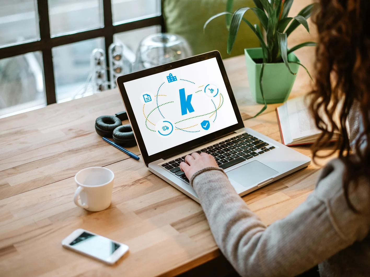 Woman working on laptop with white screen in modern office.