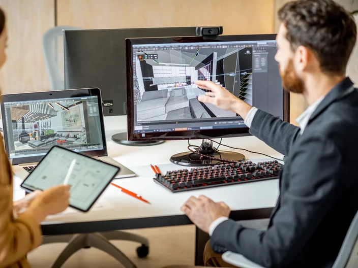 Two creative office employees making interior design on the computer and digital tablet at