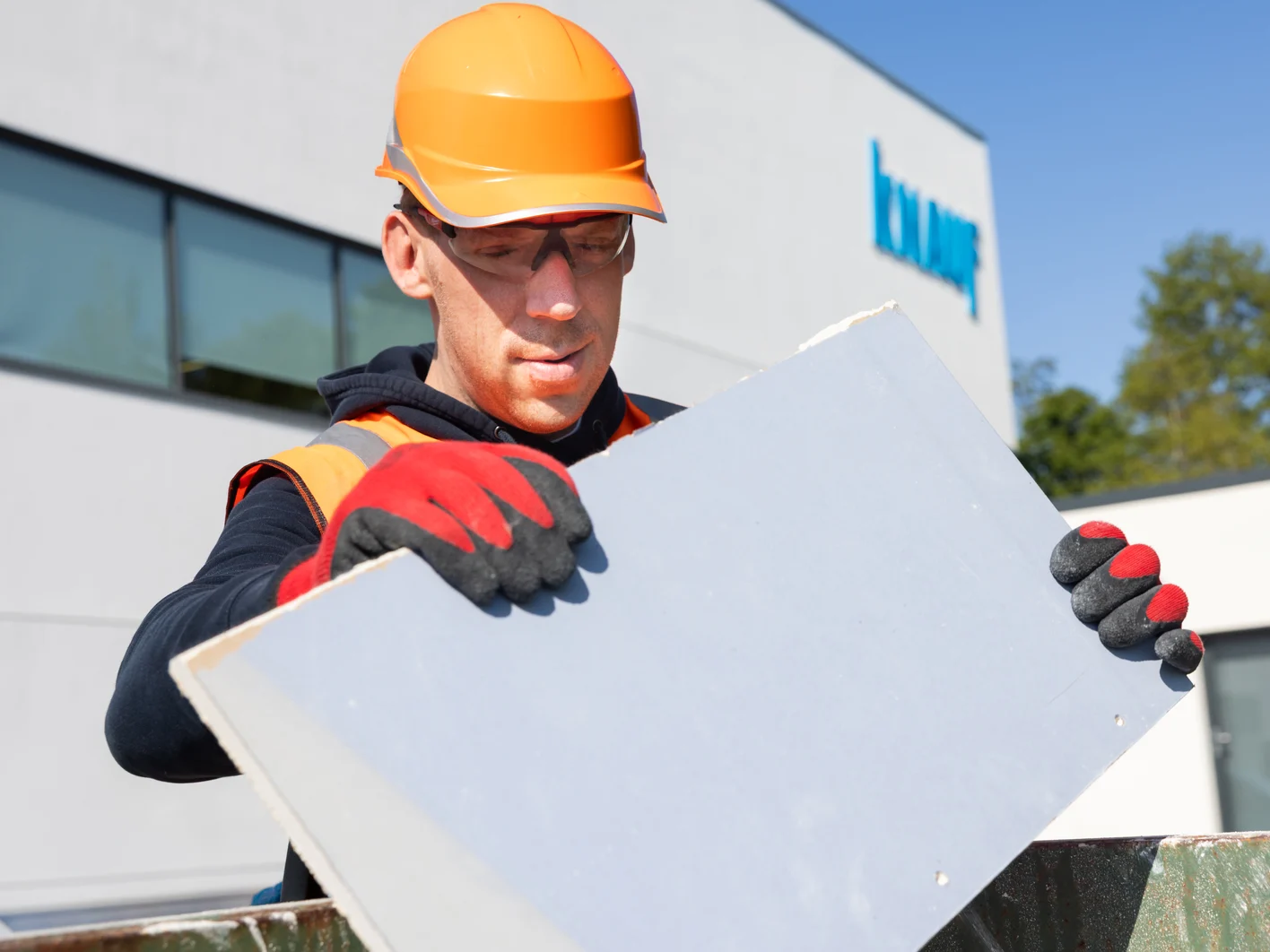 Employer in full PPE disposing of a piece of gypsum plasterboard